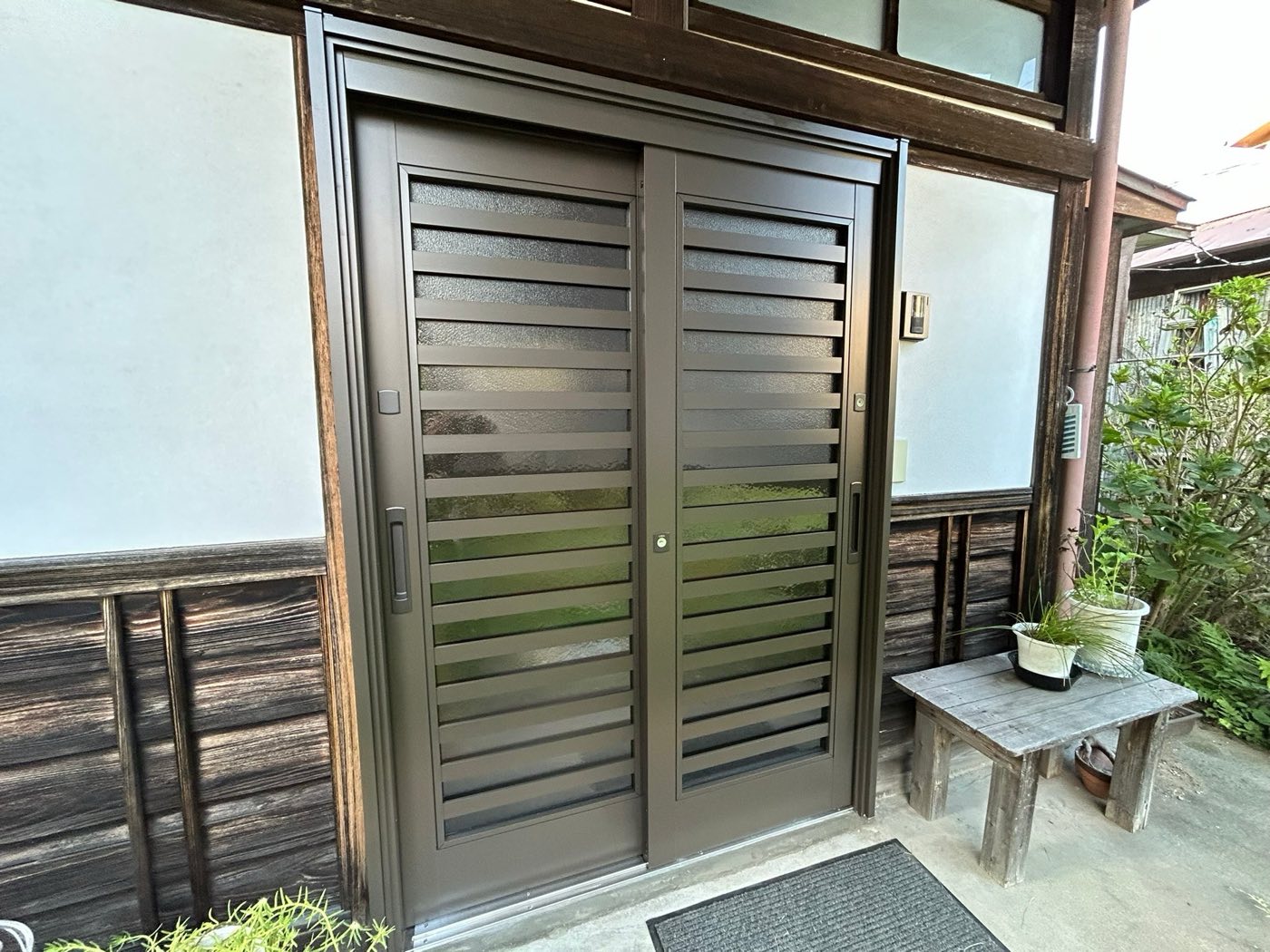 施工後の玄関。アルミ製の引き戸に交換 / The renovated entrance — click to see before and after
