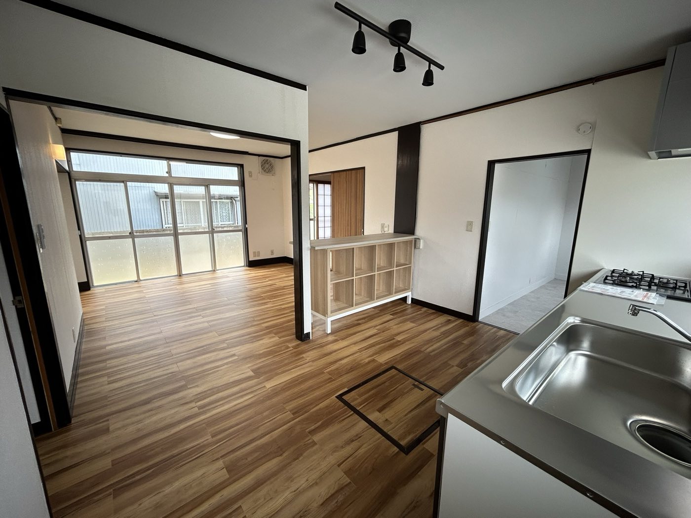 施工後のLDK。床材・照明・キッチンを一新 / The renovated LDK — click to see before and after